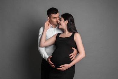 Photo of Beautiful pregnant woman with her husband on grey background