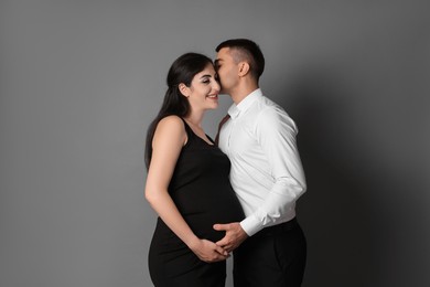 Photo of Beautiful pregnant woman with her husband on grey background