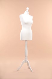 One female mannequin on stand against beige background