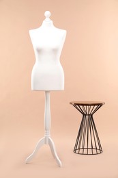 Photo of One female mannequin on stand and coffee table against beige background