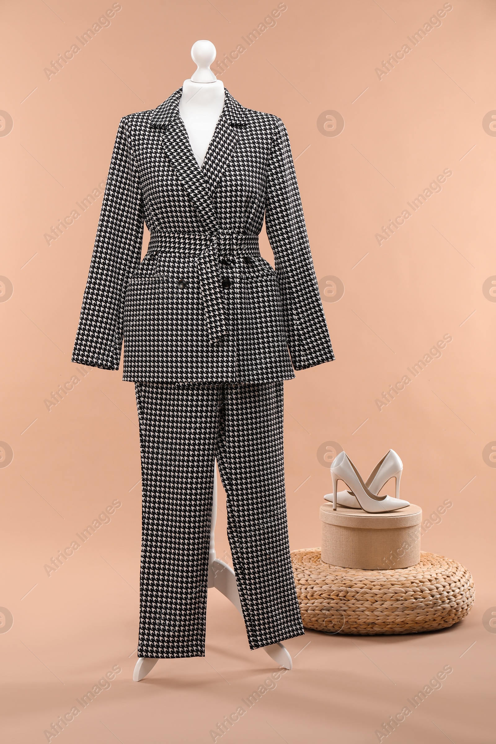 Photo of Female mannequin with suit, pouf and shoes on beige background