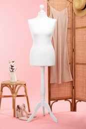 Female mannequin, folding screen with dress, stool and cotton flowers on pink background