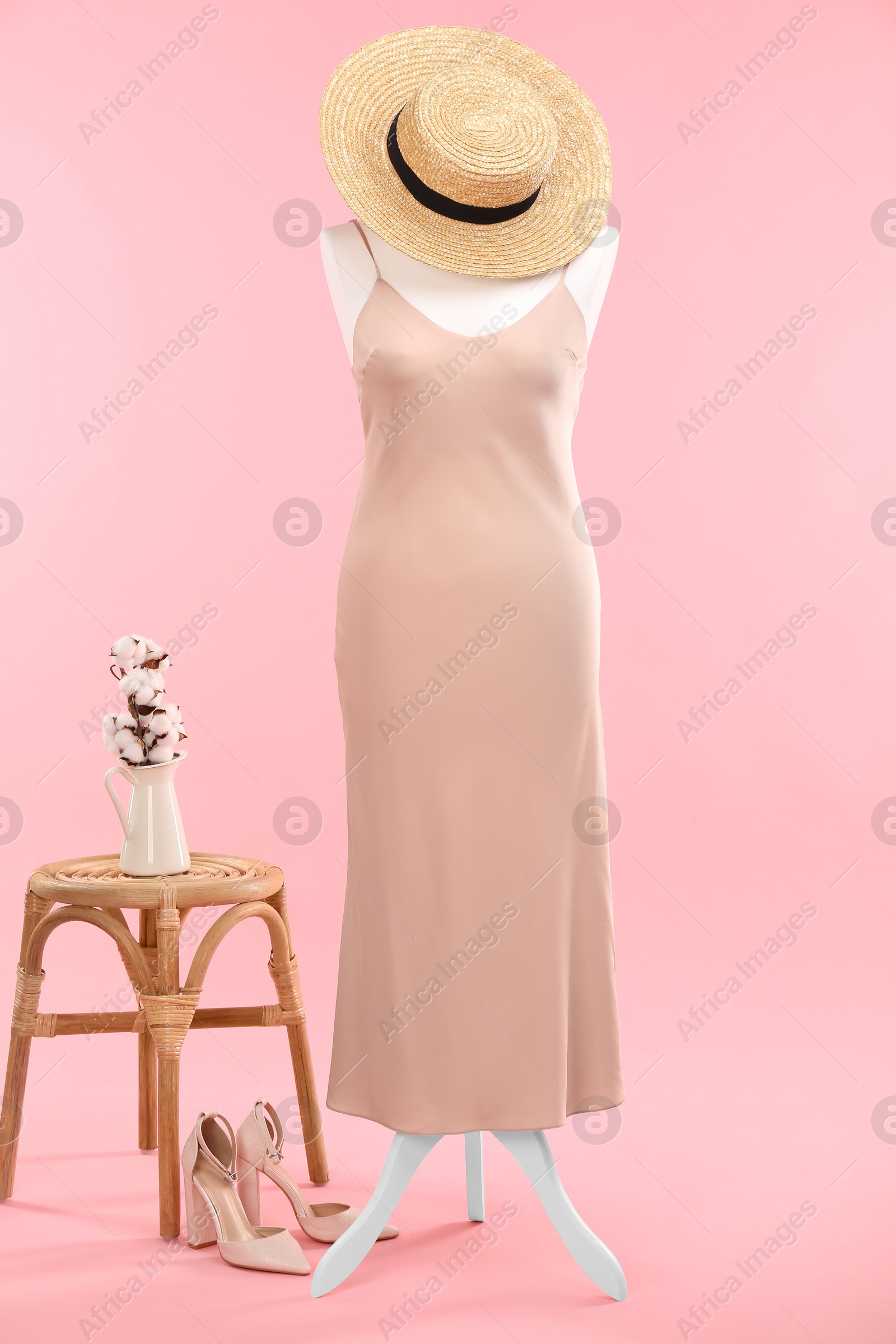 Photo of Female mannequin with dress, hat, stool and cotton flowers on pink background