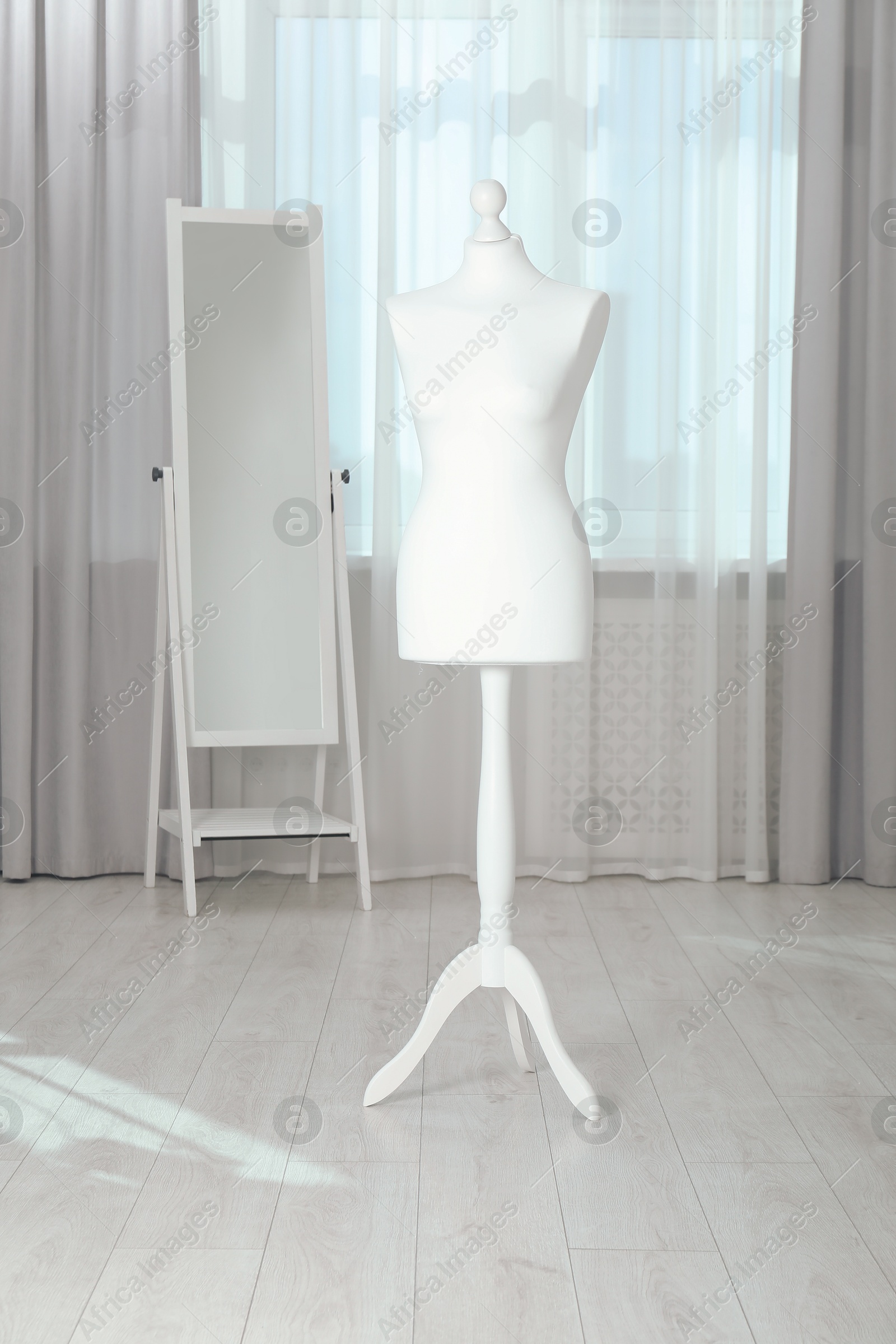 Photo of One female mannequin on stand and mirror near window indoors