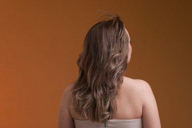 Photo of Woman with stylish haircut on brown background, back view