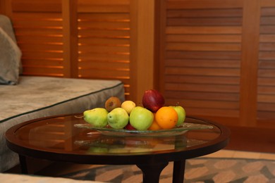 Different fresh fruits on glass table in hotel room