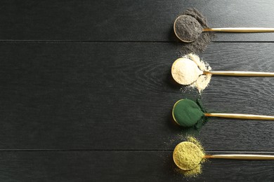 Photo of Different superfood powders in spoons on black wooden table, flat lay. Space for text