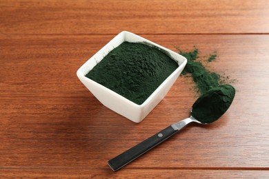 Photo of Superfood powder in bowl and spoon on wooden table, closeup