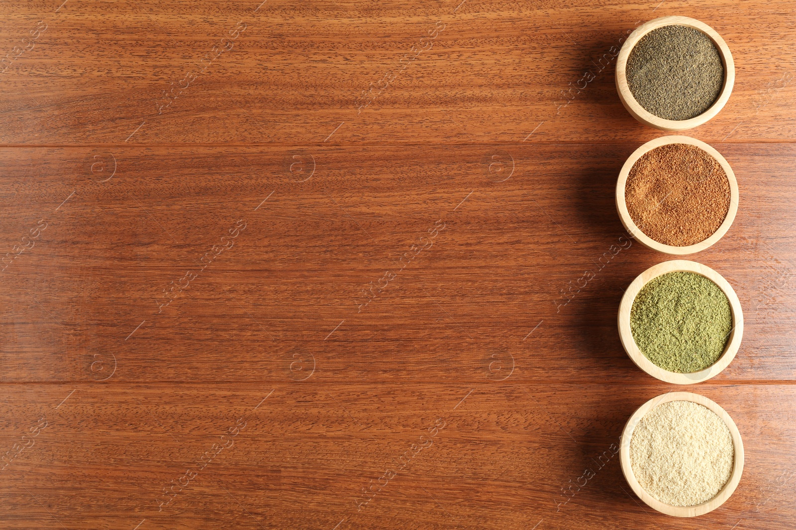 Photo of Different superfood powders in bowls on wooden table, flat lay. Space for text