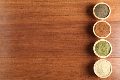 Photo of Different superfood powders in bowls on wooden table, flat lay. Space for text