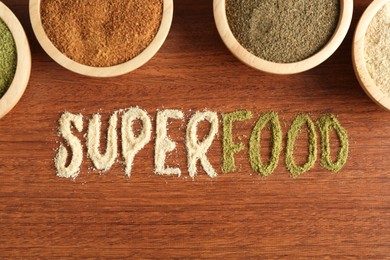 Word Superfood and different healthy powders on wooden table, flat lay