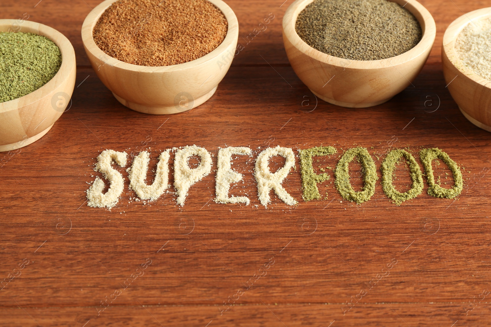 Photo of Word Superfood and different healthy powders on wooden table, closeup