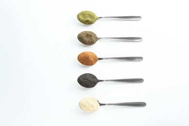 Photo of Different superfood powders in spoons on white background, above view. Space for text