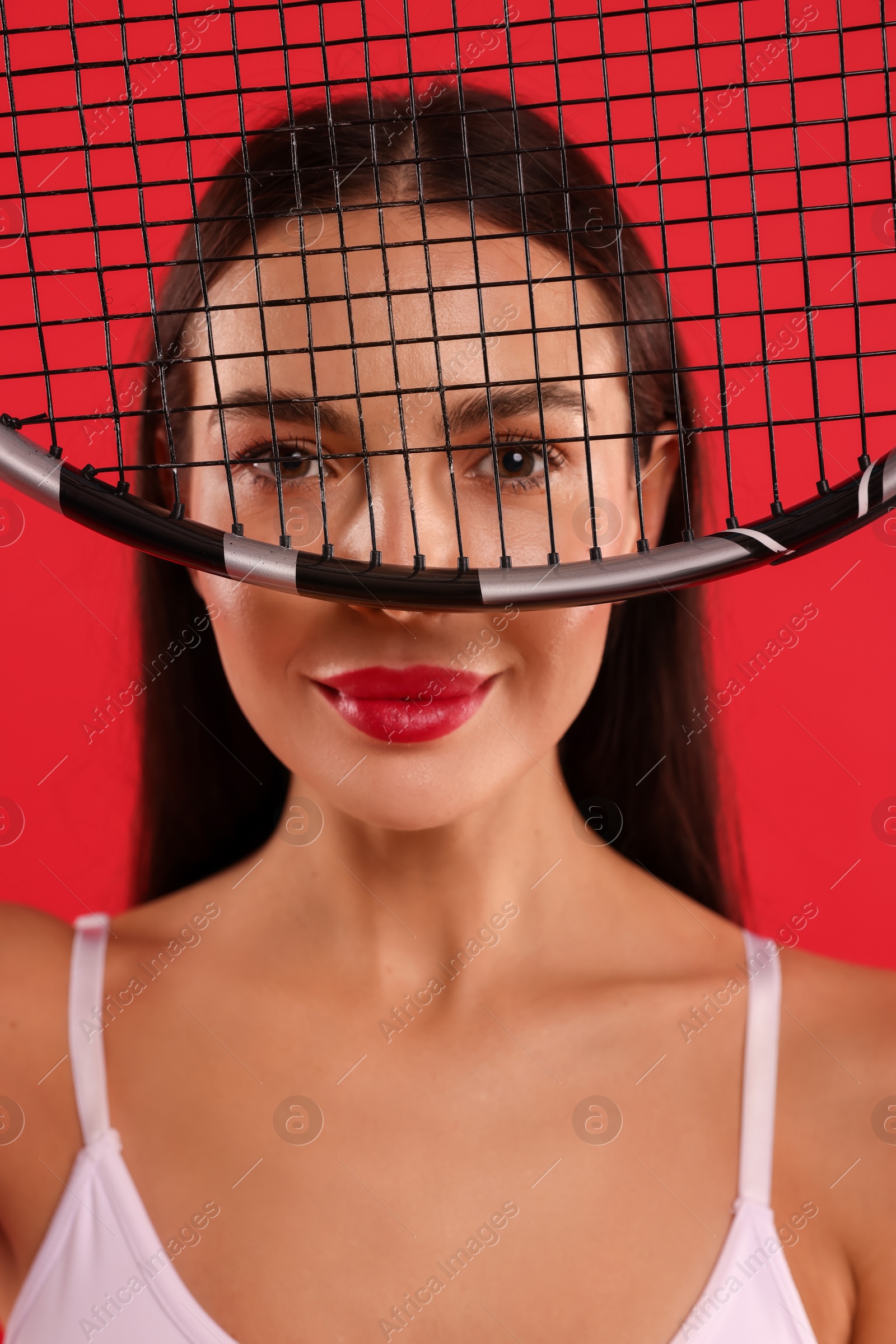 Photo of Portrait of beautiful young woman with tennis racket on red background, closeup