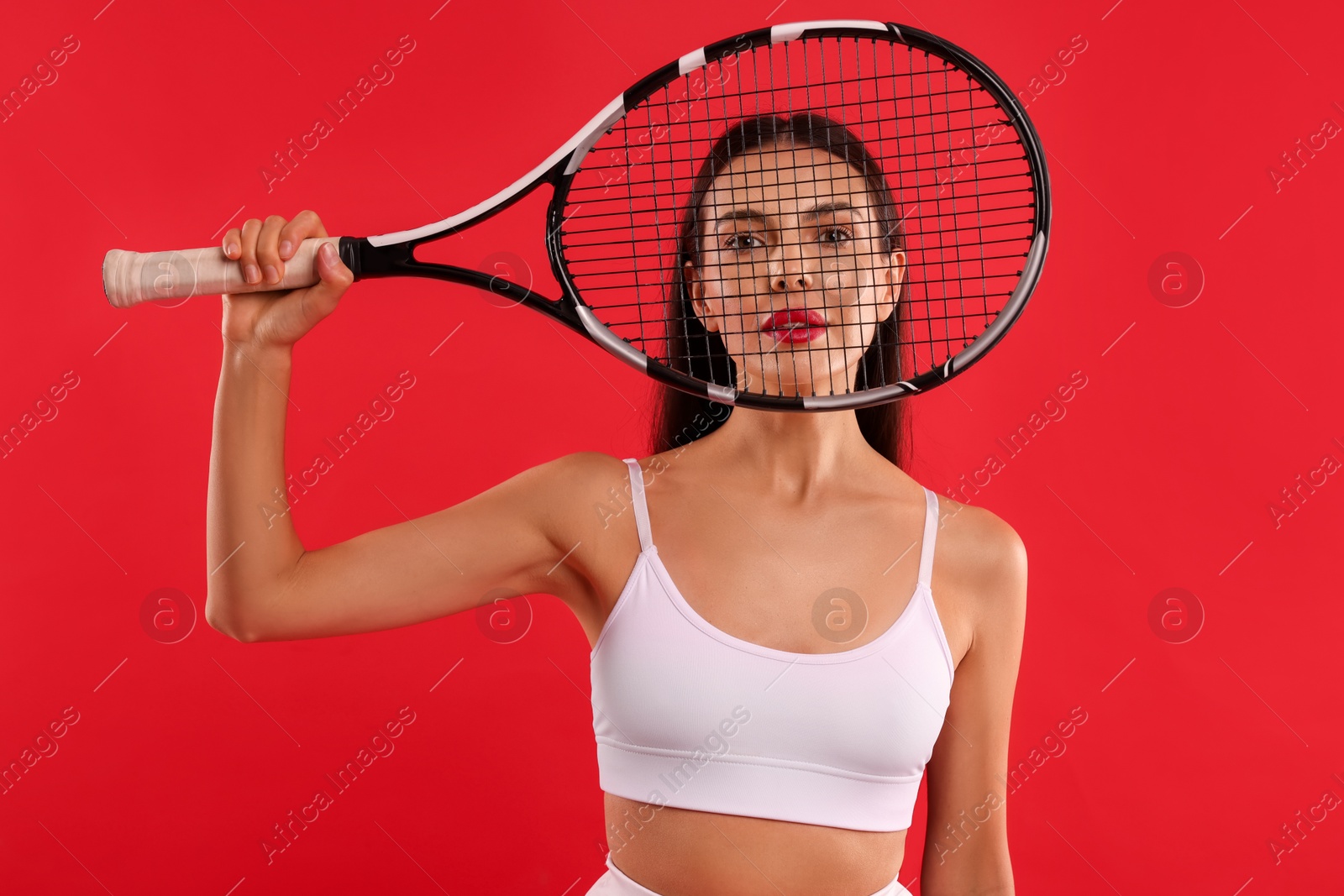 Photo of Beautiful young woman with tennis racket on red background