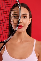 Beautiful young woman with tennis racket on red background