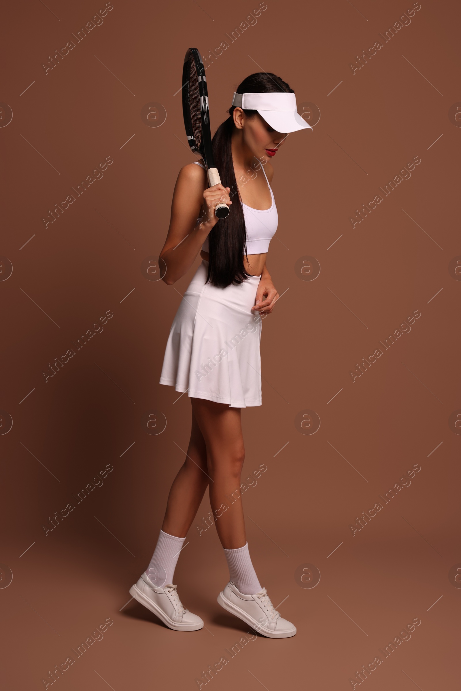 Photo of Beautiful young woman with tennis racket on brown background