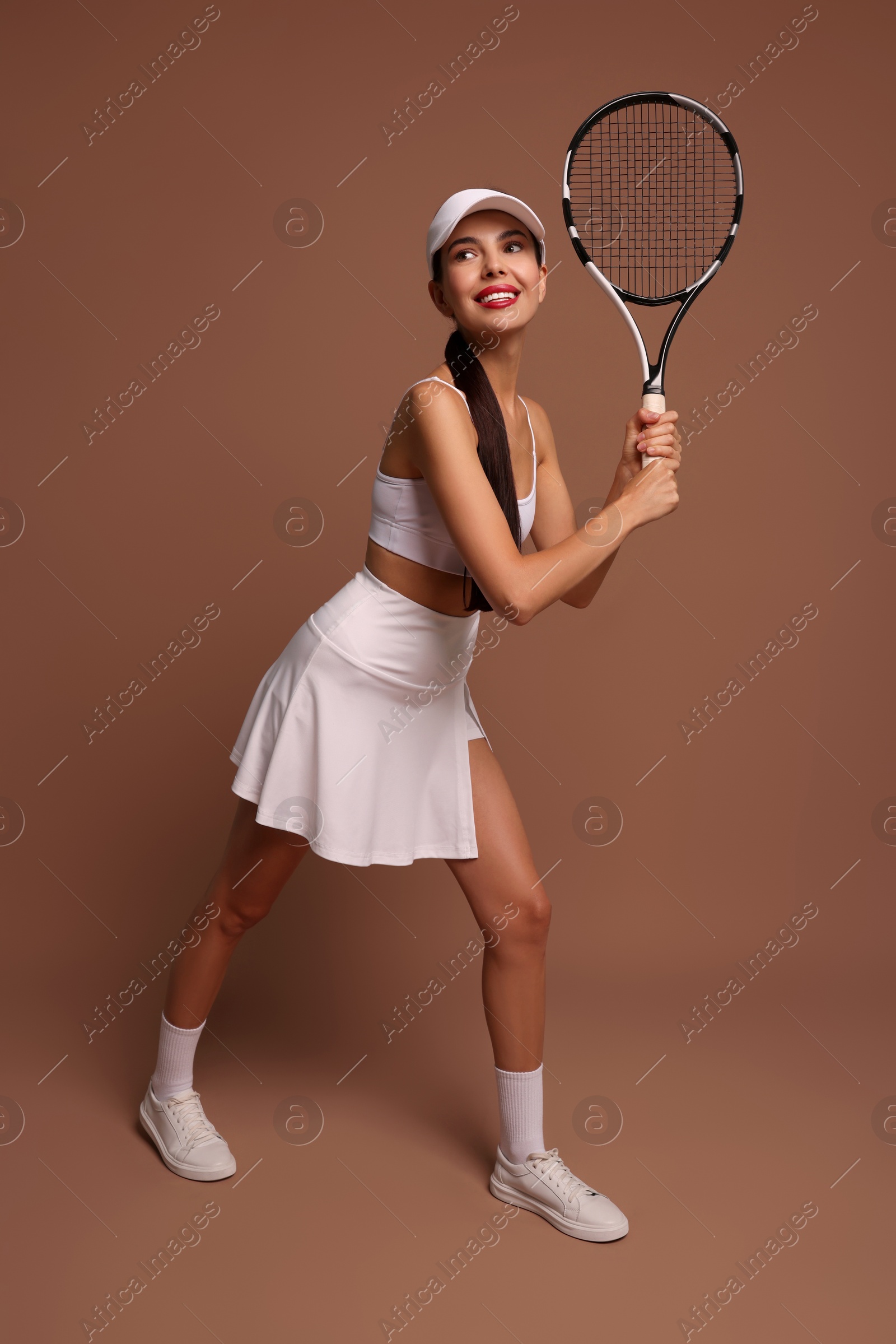 Photo of Beautiful young woman with tennis racket on brown background