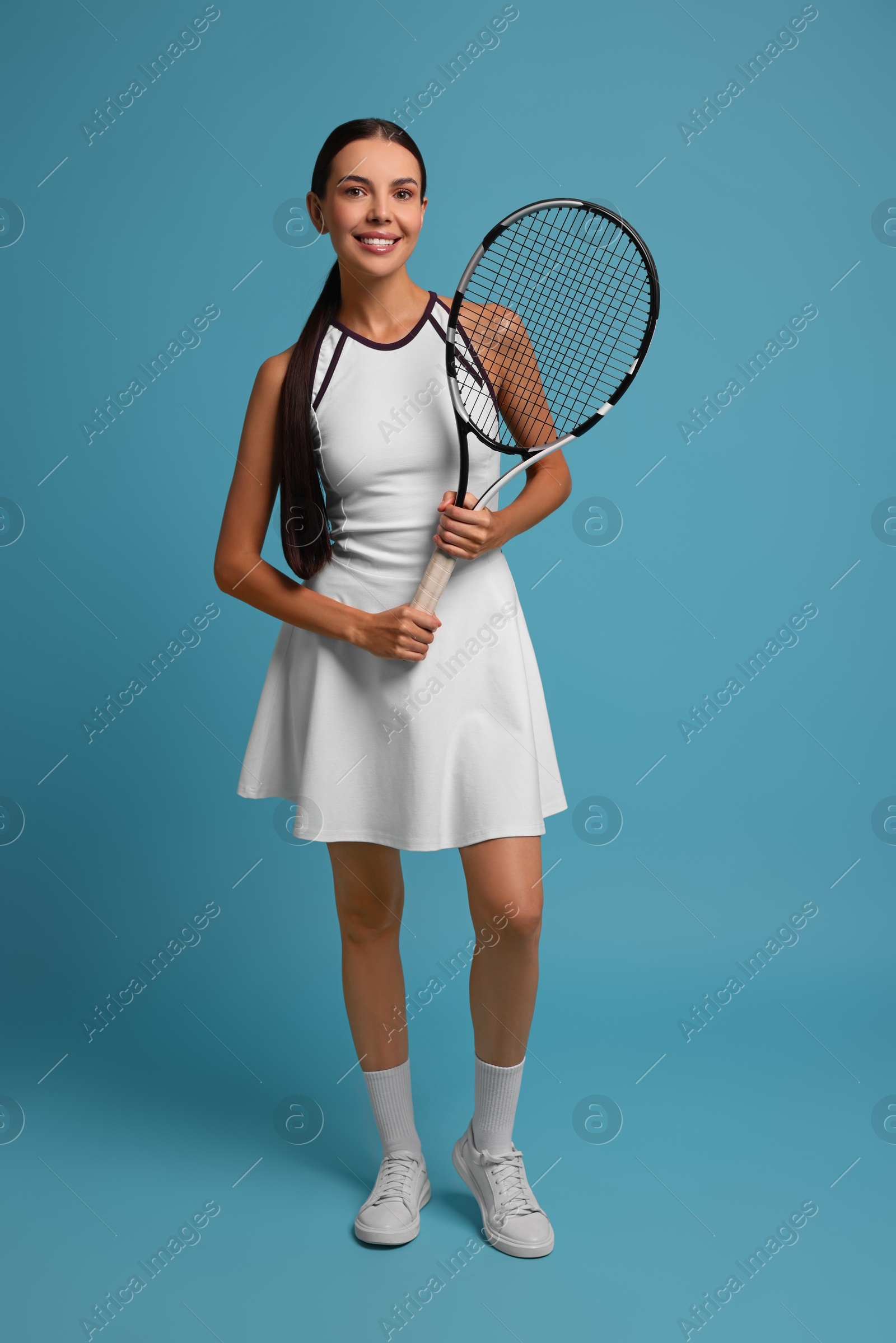 Photo of Beautiful young woman with tennis racket on light blue background