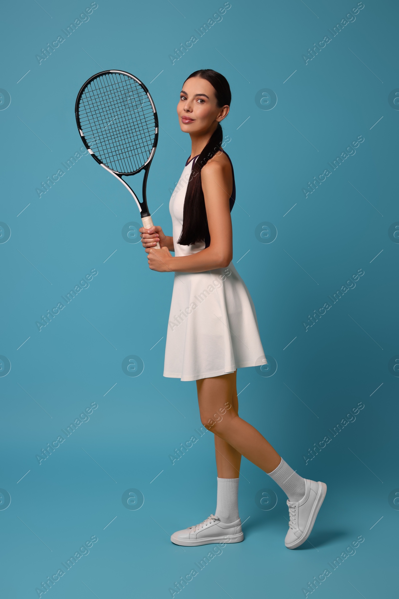 Photo of Beautiful young woman with tennis racket on light blue background