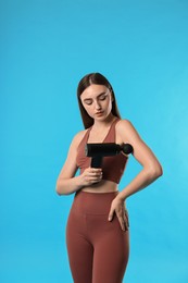 Photo of Woman using percussive massager to relieve arm muscles on light blue background