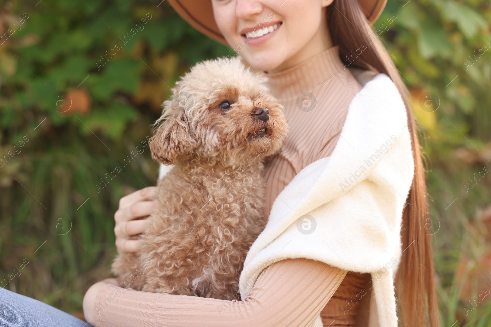 Photo of Smiling woman with cute dog in autumn park, closeup