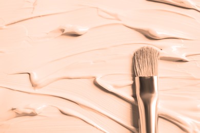 Image of Skin foundation and makeup brush as background, closeup. Peach fuzz color