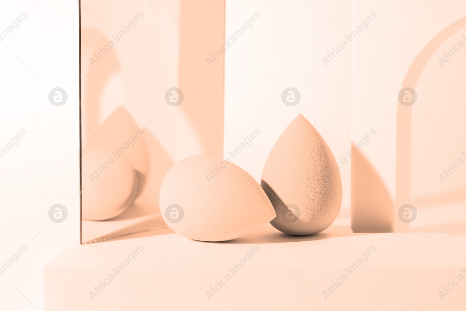 Image of Stylish presentation of makeup sponges on white background, toned in peach fuzz color