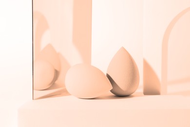 Image of Stylish presentation of makeup sponges on white background, toned in peach fuzz color