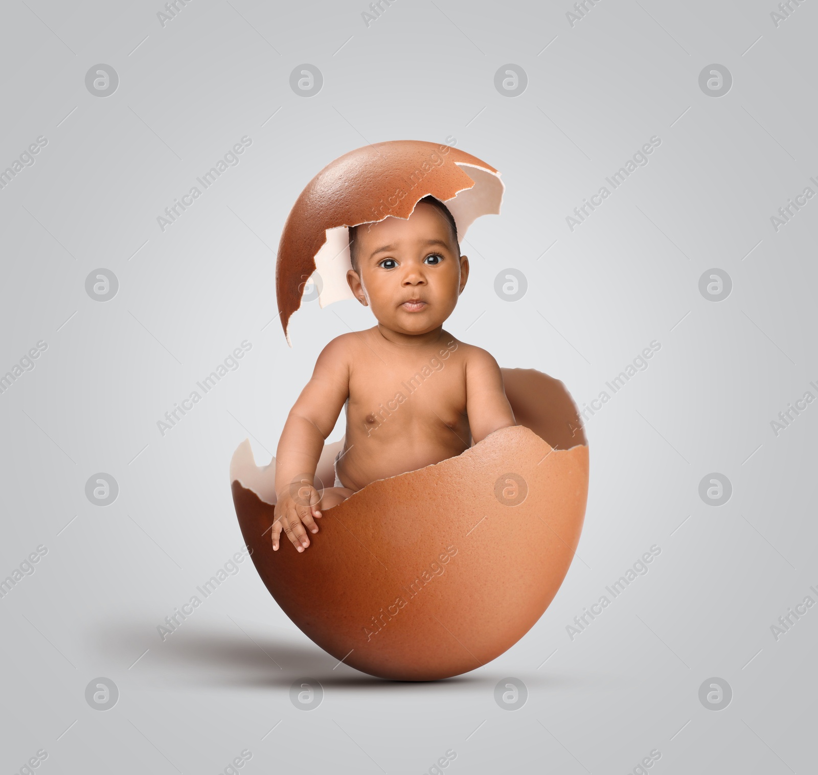 Image of Cute little baby in eggshell on light grey background