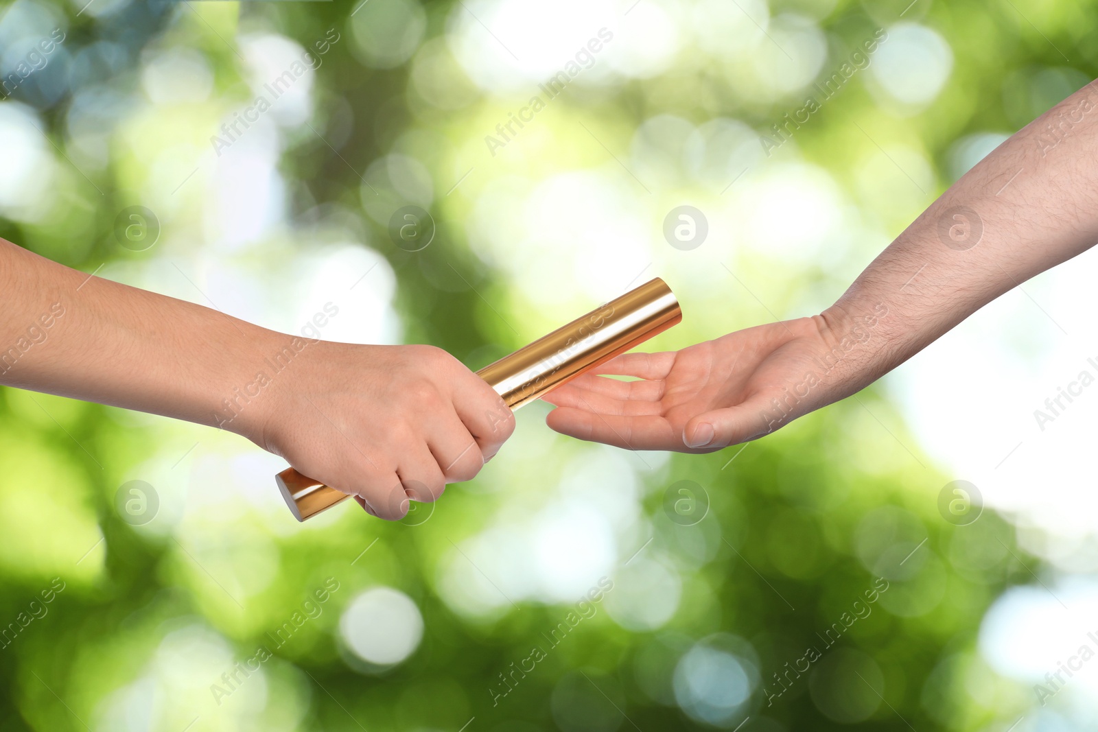 Image of Man passing relay baton to teammate outdoors, closeup