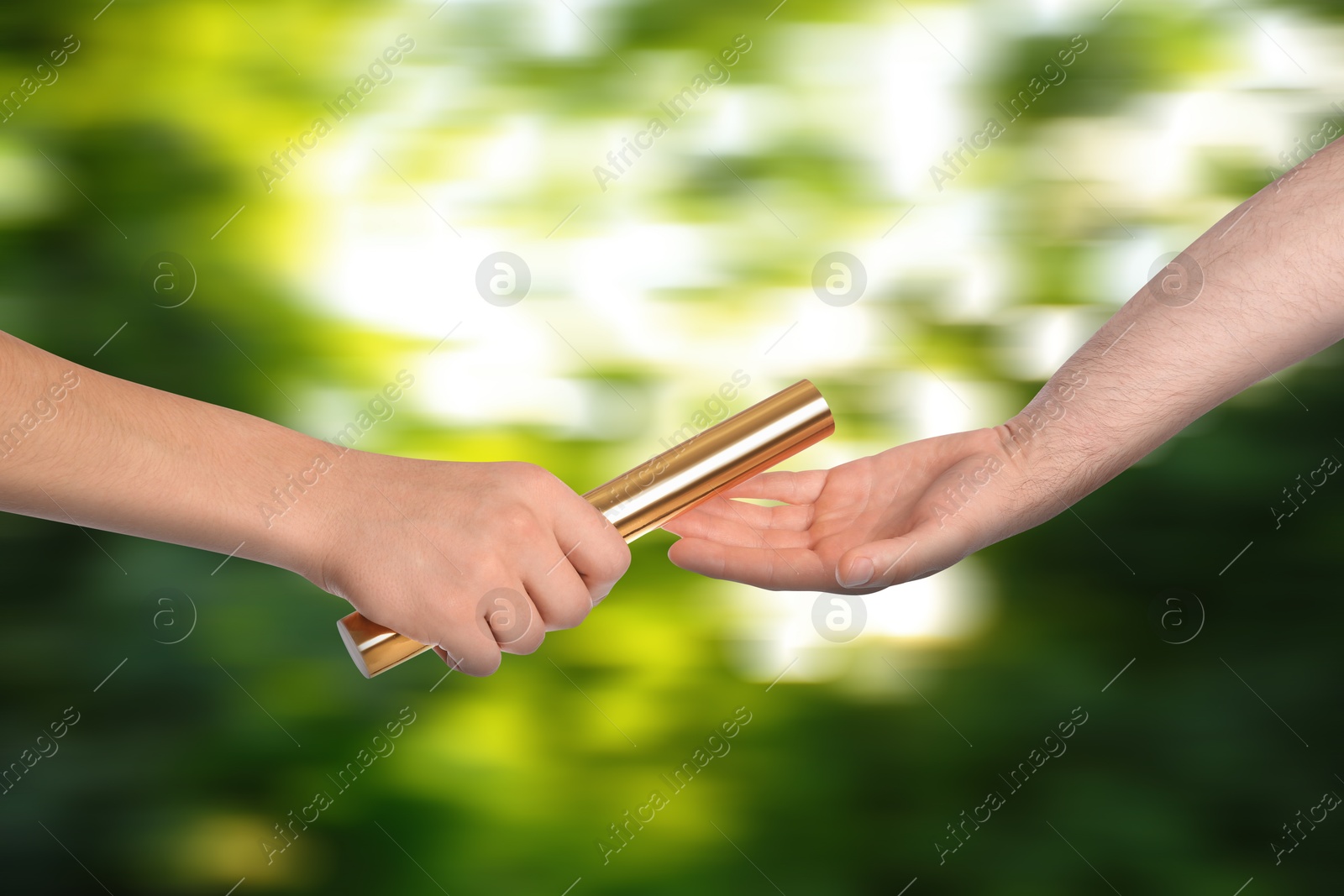 Image of Man passing relay baton to teammate outdoors, closeup