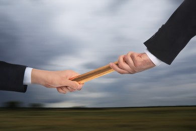 Image of Businessman passing relay baton to colleague outdoors, closeup