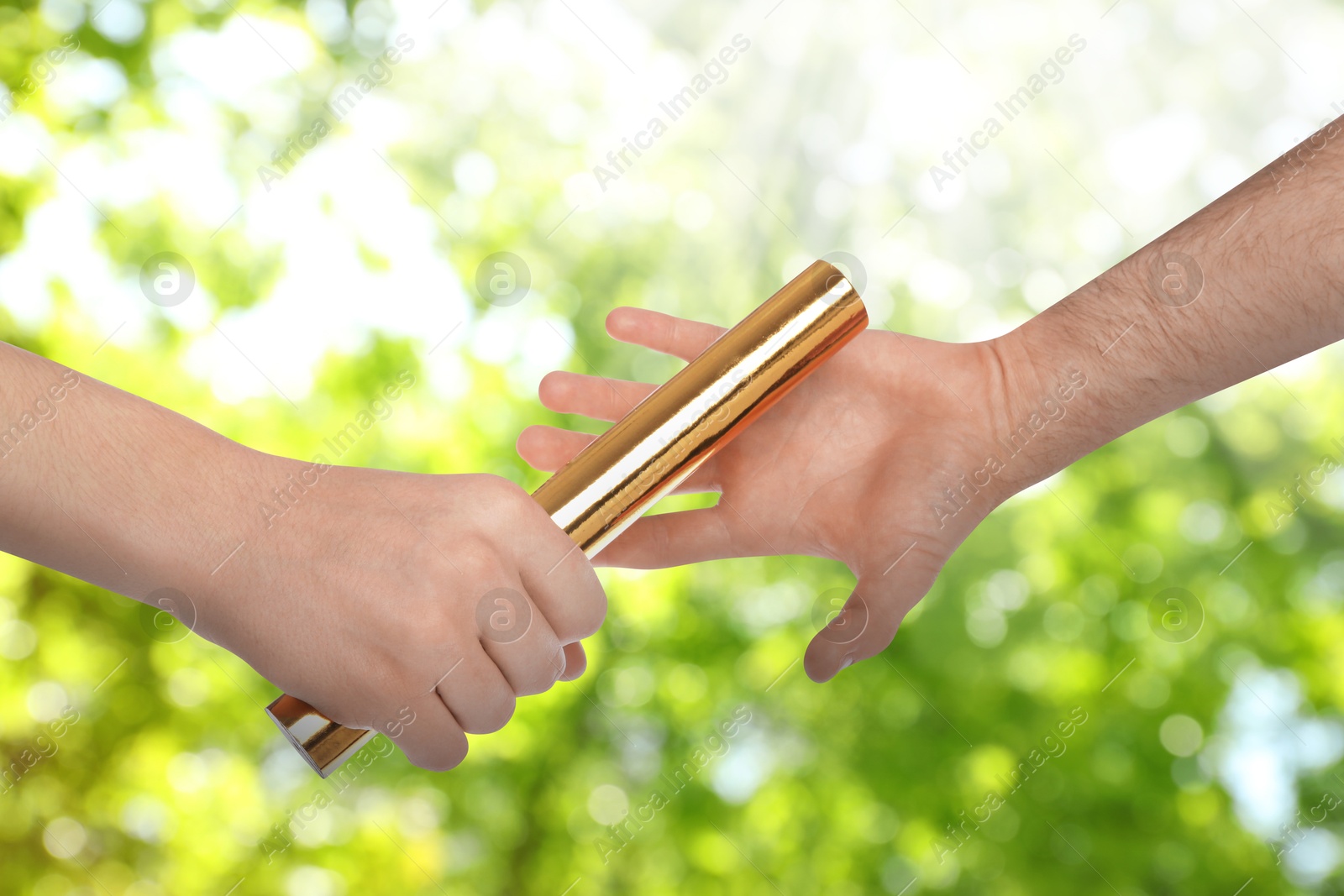 Image of Man passing relay baton to teammate outdoors, closeup