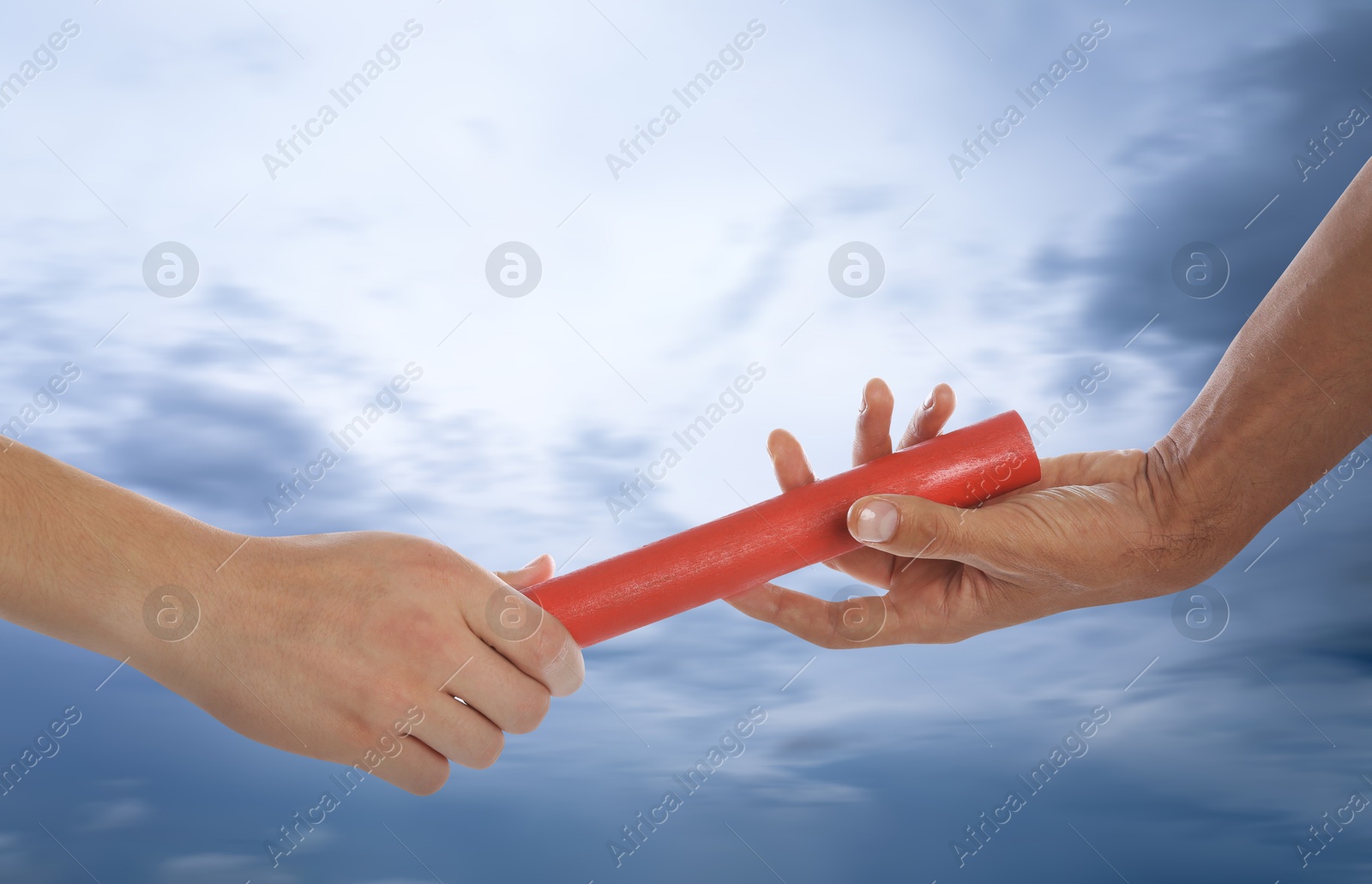 Image of Man passing relay baton to teammate outdoors, closeup