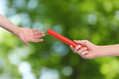 Image of Woman passing baton to man outdoors, closeup