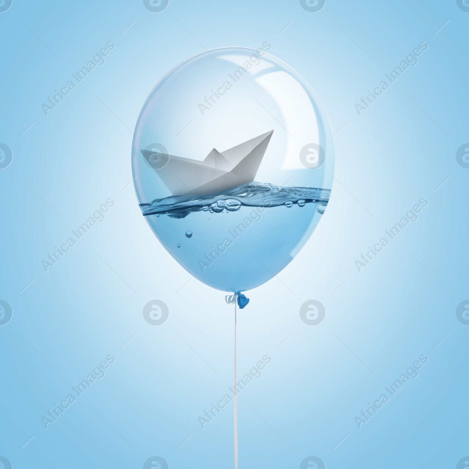 Image of Paper boat floating on water inside balloon against light blue background