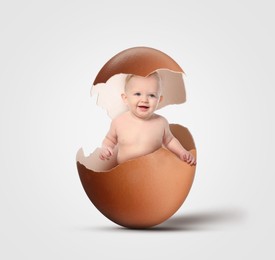 Image of Cute little baby in eggshell on light grey background