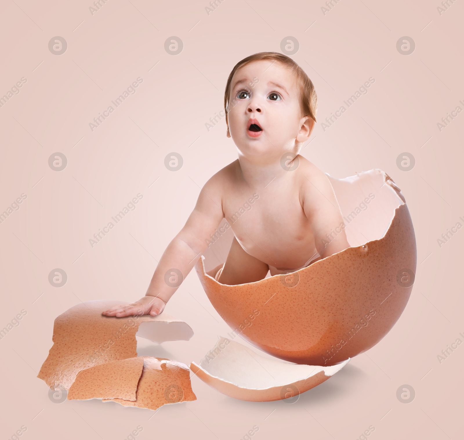 Image of Cute little baby in eggshell on pink background