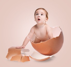 Image of Cute little baby in eggshell on pink background