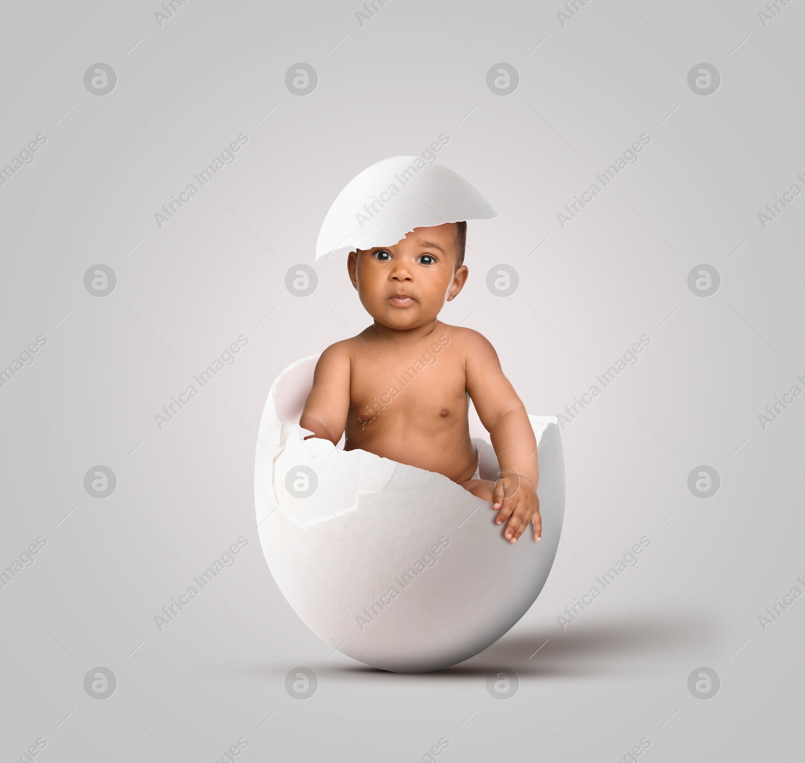 Image of Cute little baby in eggshell on light grey background