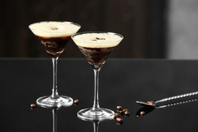 Refreshing cocktails in glasses, spoon and coffee beans on black table