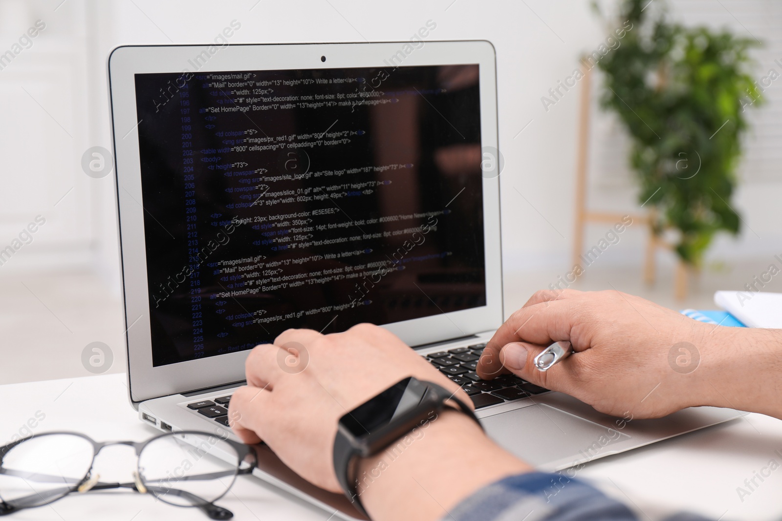 Photo of Programmer working with laptop at white desk in office, closeup