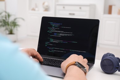 Photo of Programmer working with laptop at white desk in office, closeup