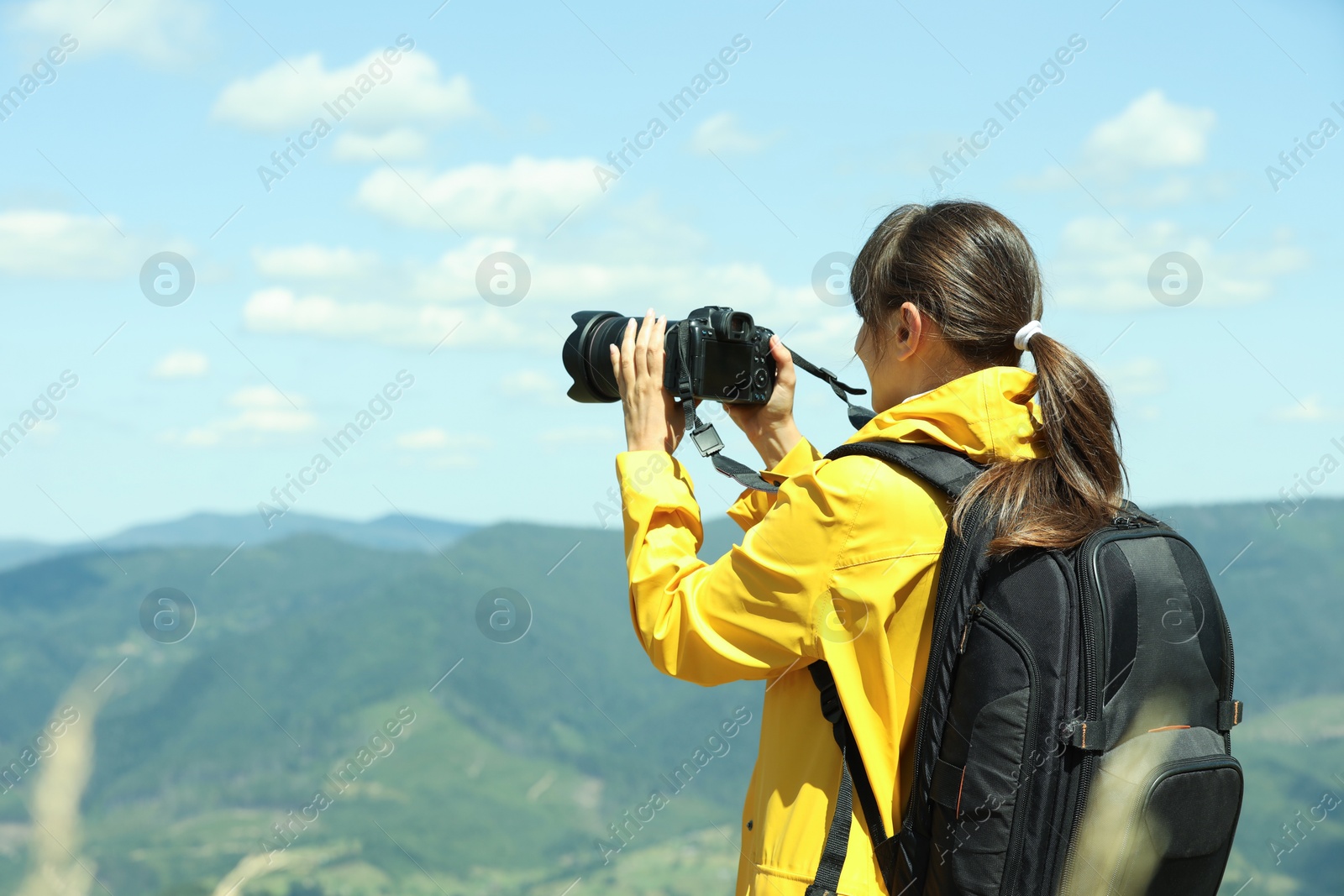 Photo of Photographer with backpack and camera taking picture of beautiful mountains