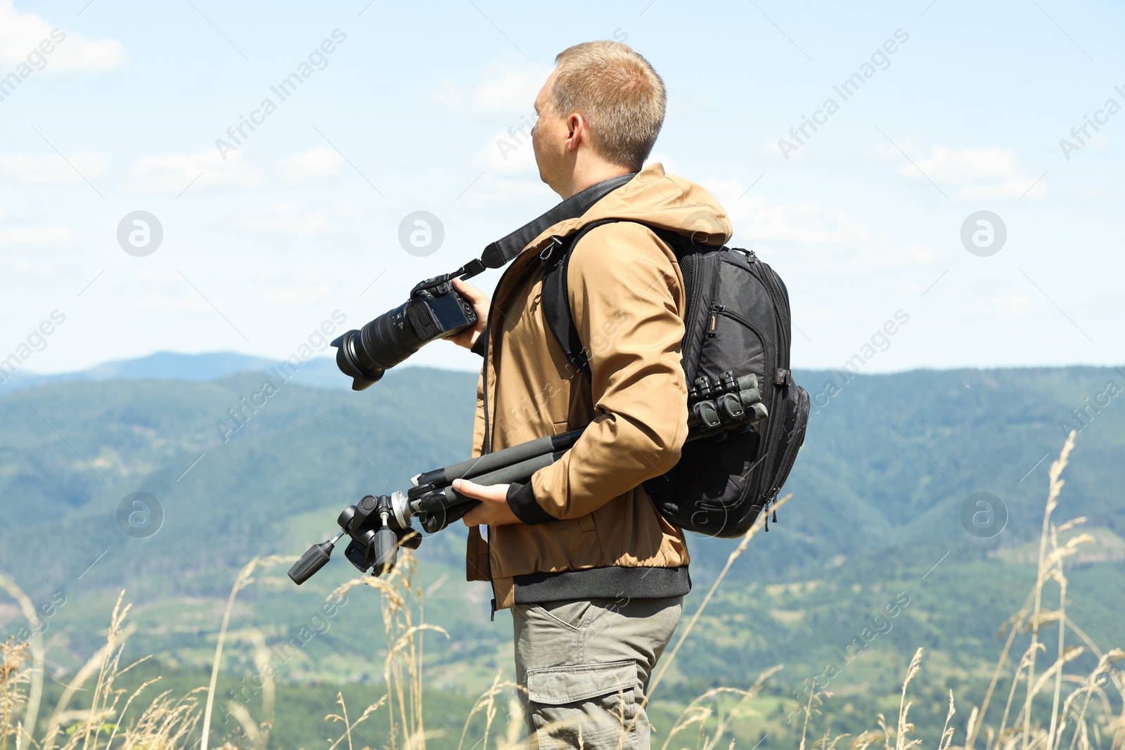 Photo of Photographer with backpack, camera and other professional equipment in mountains