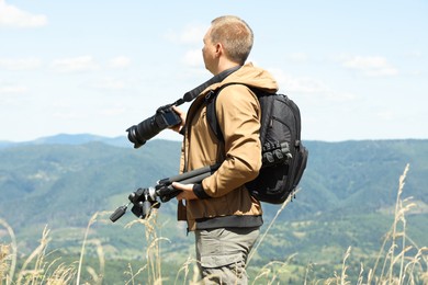 Photographer with backpack, camera and other professional equipment in mountains