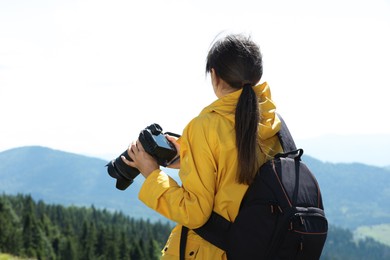 Photo of Photographer with backpack and camera in mountains, back view