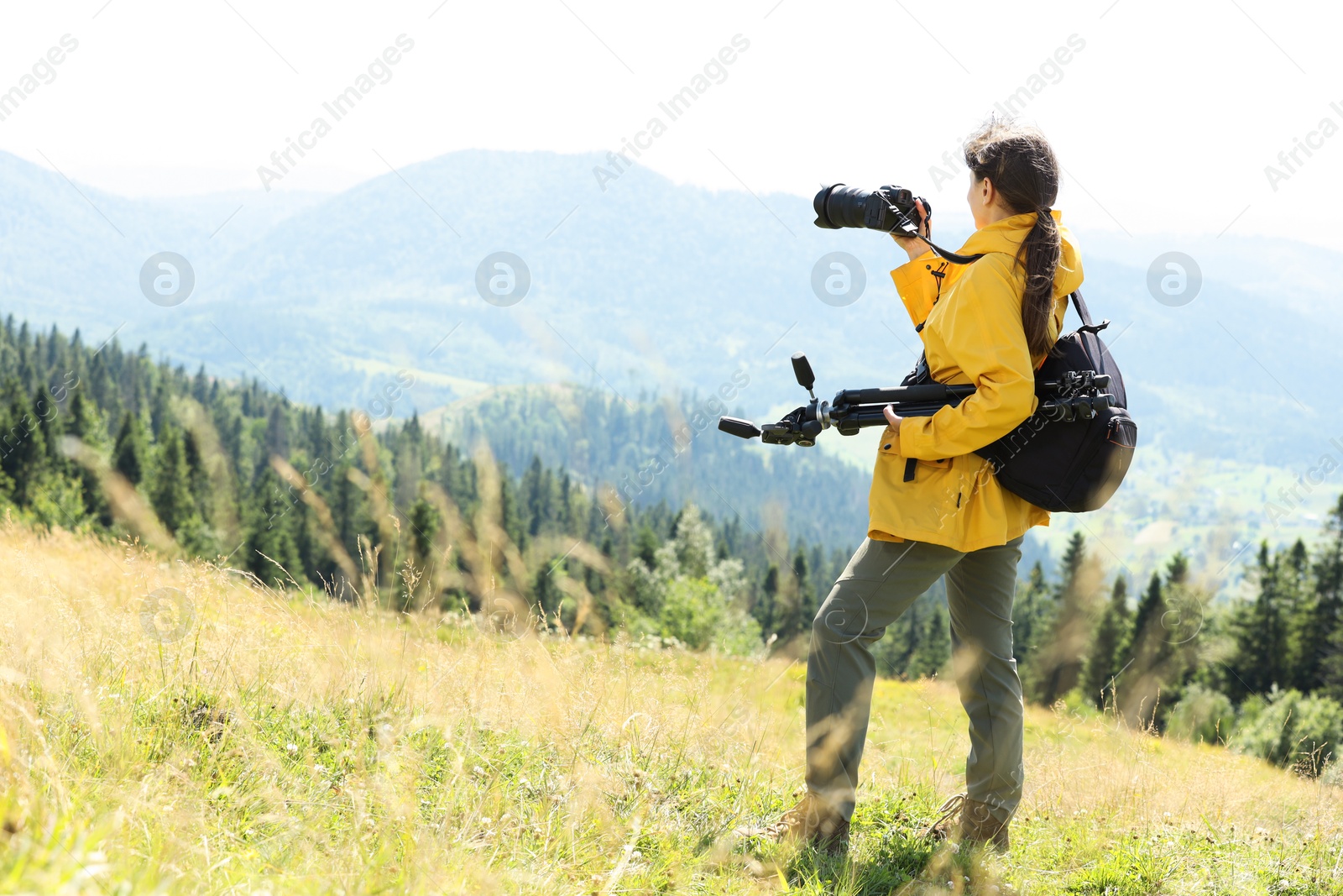 Photo of Photographer with backpack and camera taking picture of beautiful mountains. Space for text