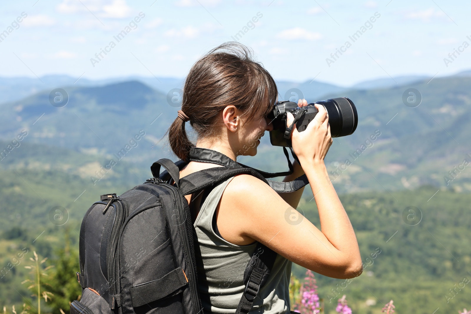 Photo of Photographer with backpack and camera taking picture of beautiful mountains